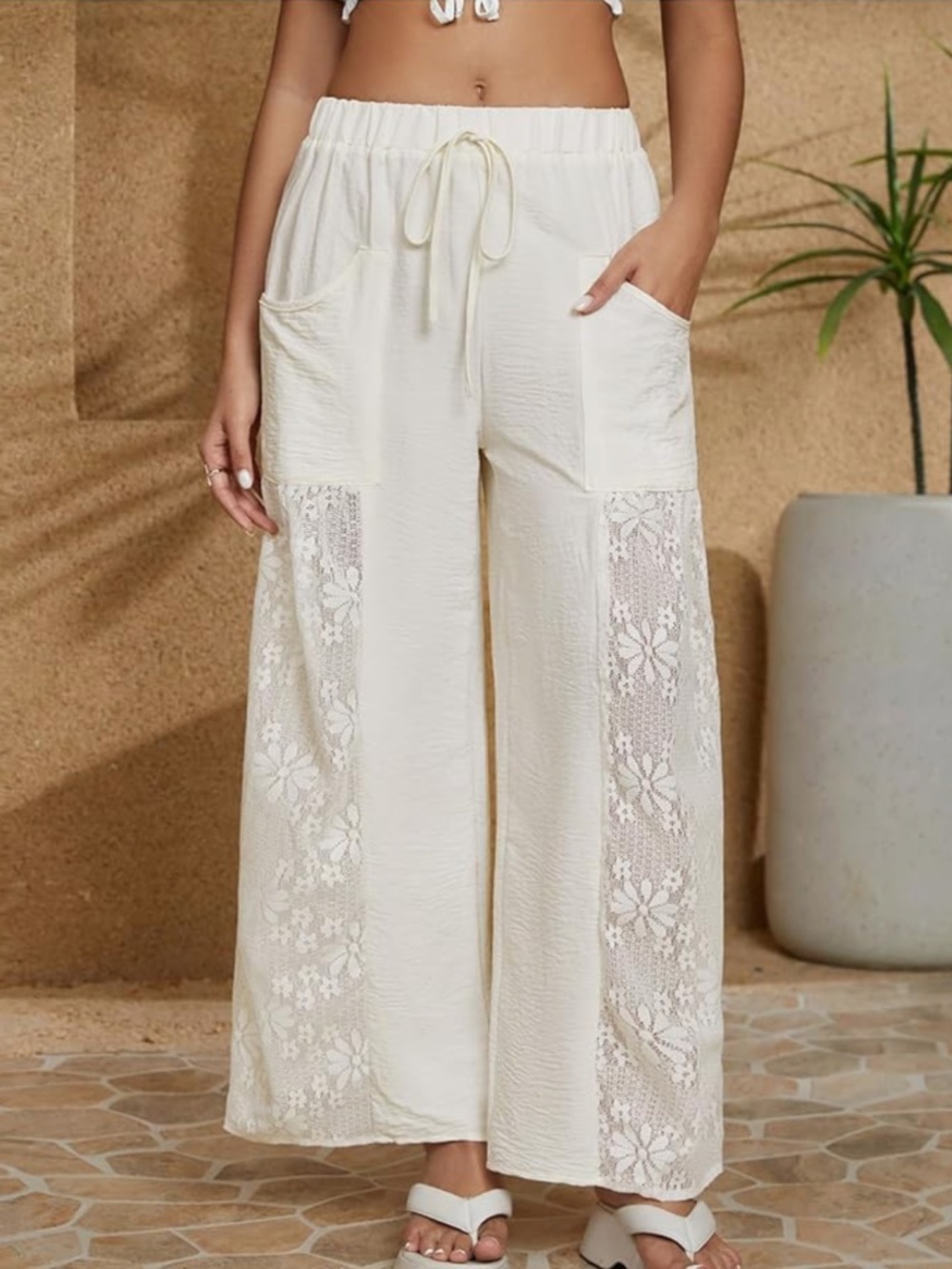 Lightweight cream wide-leg pants with floral lace side panels. Elastic drawstrin